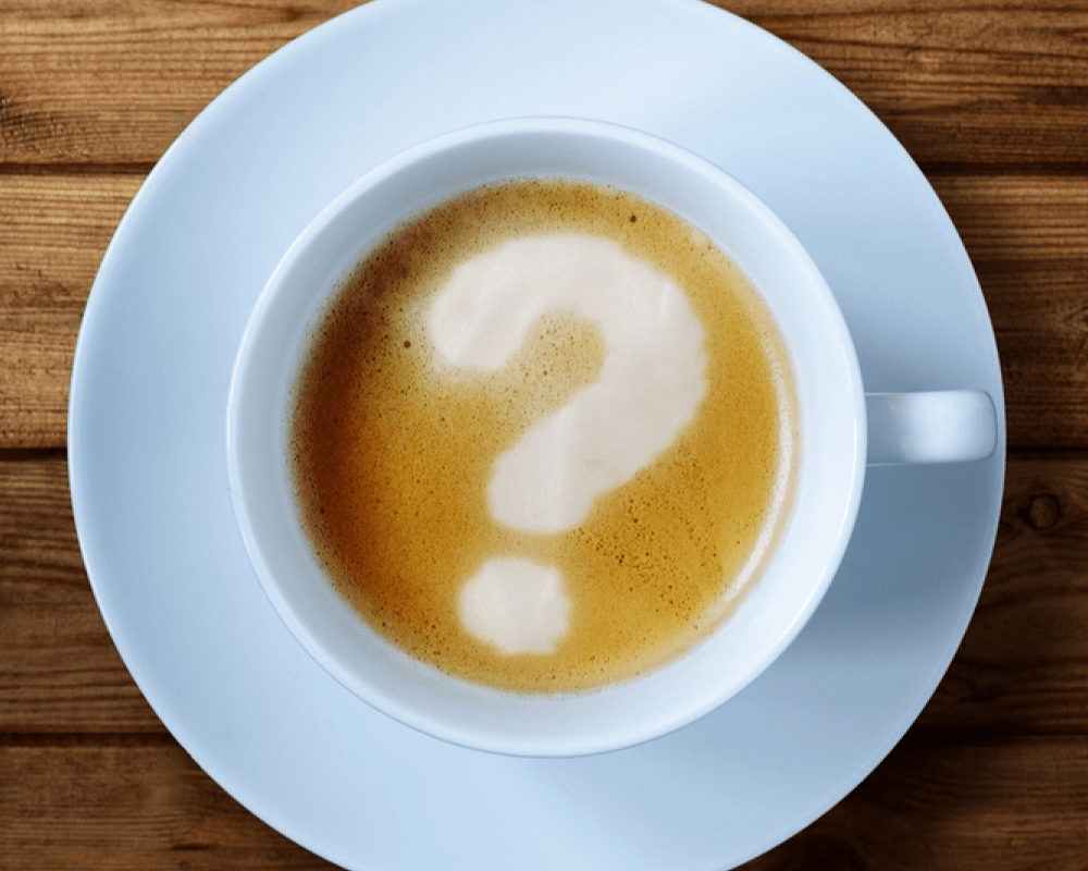 Coffee mug with a question mark formed out of foam